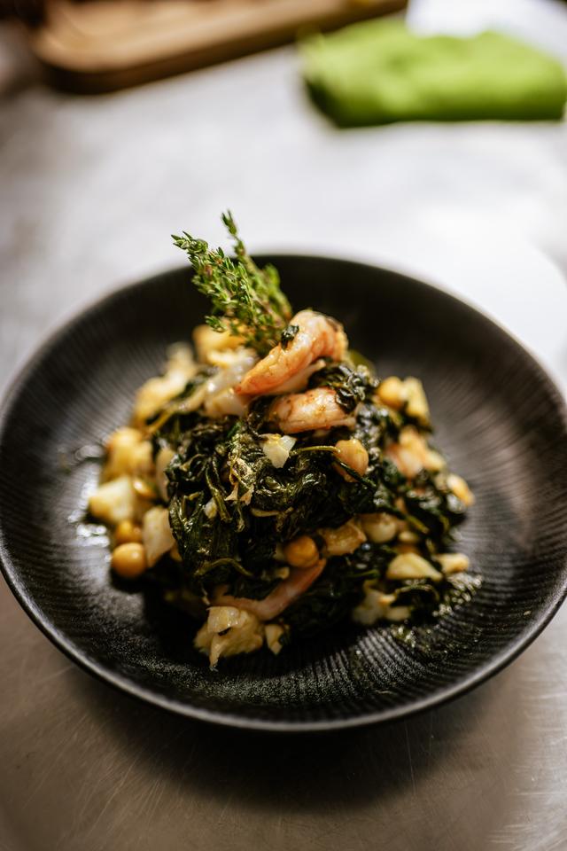 Plato de verduras con garbanzos y gambas en cuenco negro