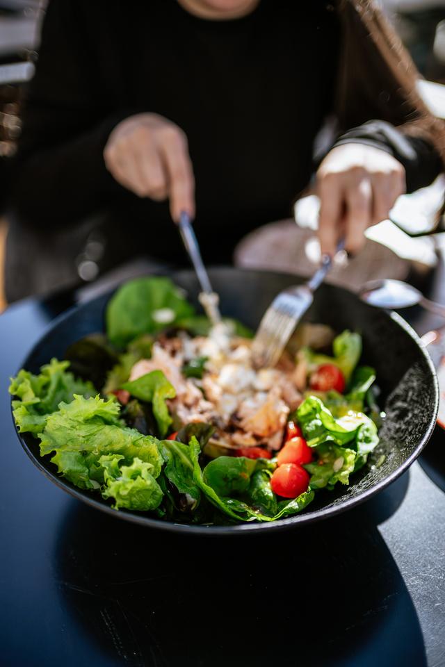 Comensales sirviéndose una ensalada en la mesa